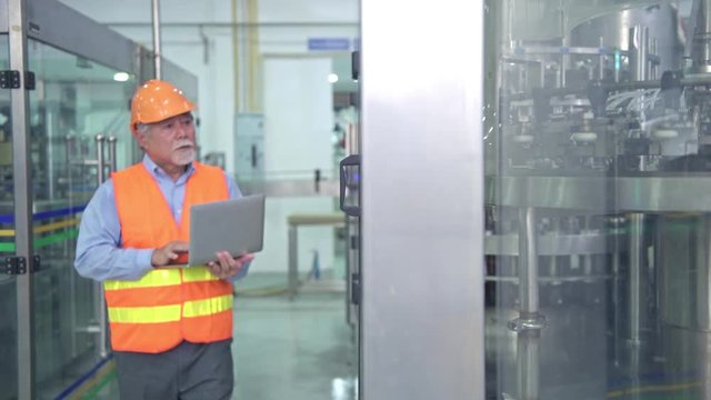 Quality inspection in factory. Senior chinese quality assurance team inspecting a liquid filling bottle machine in factory using TQM, TPM methodology. Excellence manufacturing concept.