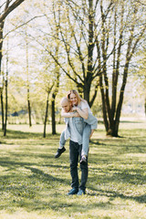 Naklejka premium Beautiful young couple in the Park on a Sunny day, loving and happy. Walk and laugh with the dog. Pre-wedding shooting in nature. Casual style in clothing and European in processing