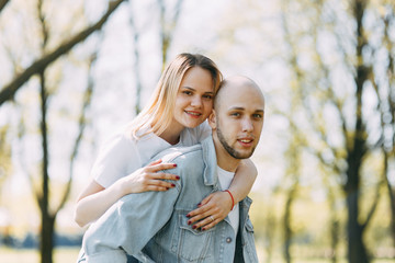 Fototapeta premium Beautiful young couple in the Park on a Sunny day, loving and happy. Walk and laugh with the dog. Pre-wedding shooting in nature. Casual style in clothing and European in processing