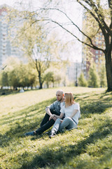 Naklejka na ściany i meble Beautiful young couple in the Park on a Sunny day, loving and happy. Walk and laugh with the dog. Pre-wedding shooting in nature. Casual style in clothing and European in processing