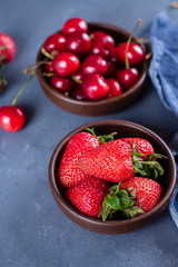 Summer Berries Strawberry and Cherry in wooden plate on blue concrete table background. Healthy Food Concept.