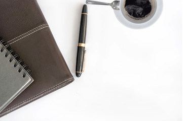 notebook pen and coffee cup on white desk