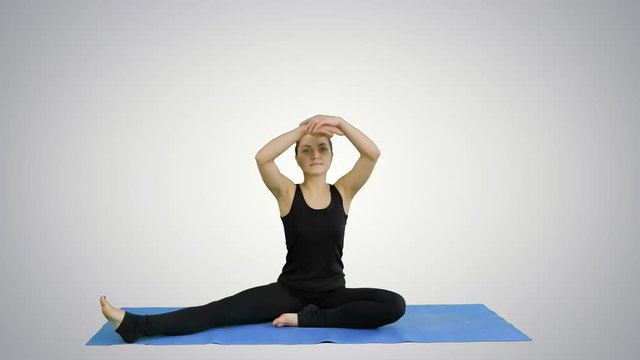 Young woman stretching her legs while doing yoga practice on white background