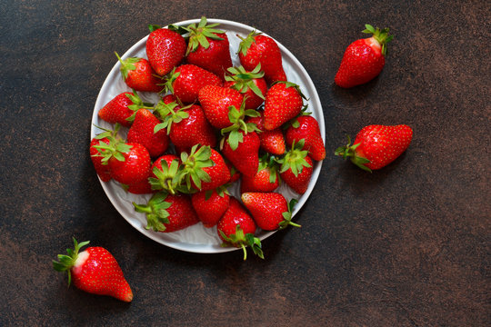 Fresh, juicy strawberries in a plate on a dark rustic background. Proper nutrition. Organic food.
