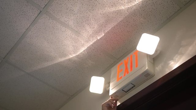 Woman testing an exit sign alarm in an office