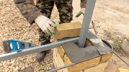 man builds a brick wall at a construction site