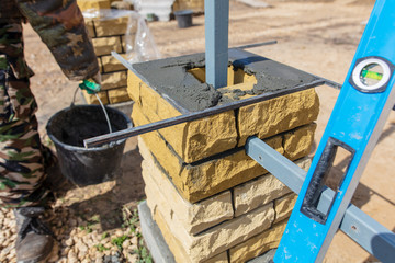 man builds a brick wall at a construction site
