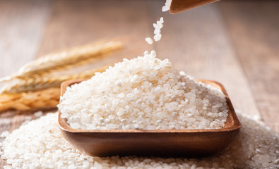 raw rice in a wooden bowl on wooden background