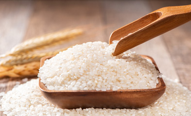raw rice in a wooden bowl on wooden background