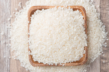 raw rice in a wooden bowl on wooden background