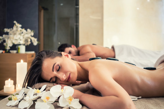 Young couple relaxing under the stimulating effects of a traditional hot stone massage at luxury spa and wellness center