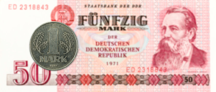 1 mark coin against historic 50 east german mark bank note