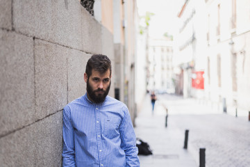 joven apuesto en la calle apoyado en una pared