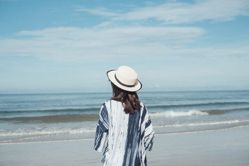 traveler young woman in casual dress with hat stand alone on beach has blue sky and sea background