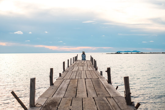 traveler young woman in sit alone on wood bridge has sunset and sea background
