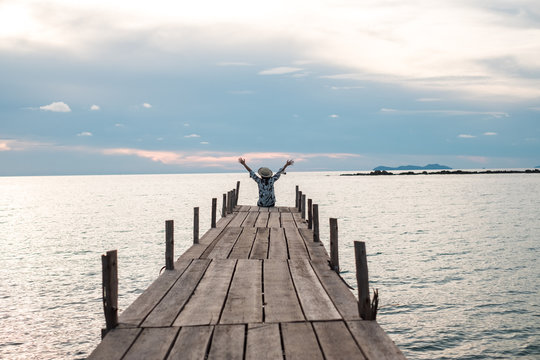 traveler young woman in sit alone on wood bridge has sunset and sea background