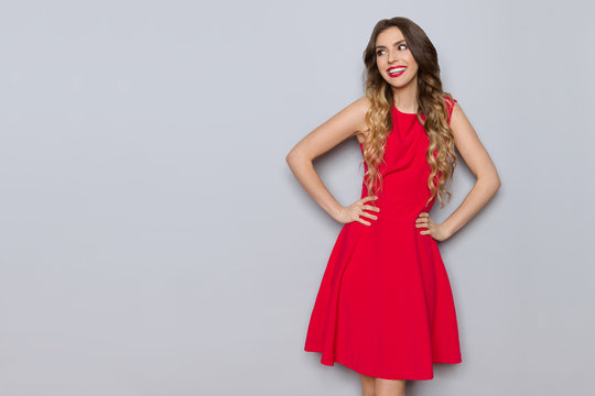Smiling Young Woman In Elegant Red Dress Is Looking Away