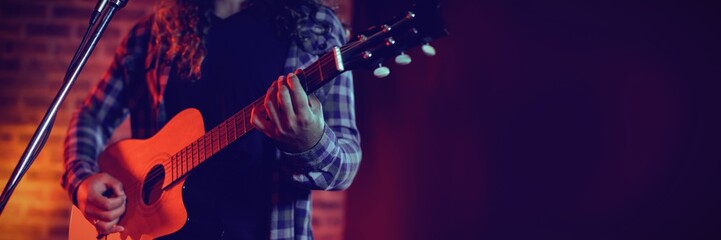 Mid section of singer playing guitar while singing - Powered by Adobe