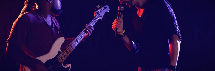 Male singer with guitarist performing at music concert