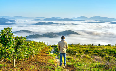 Naklejka na ściany i meble Silhouette young man standing on a high hill scenic rural hometown in the morning valley fog shrouded mountains looming large undulating scenic spot for the native Vietnam