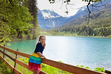Fototapeta na wymiar Child hiking in flower field at mountain lake
