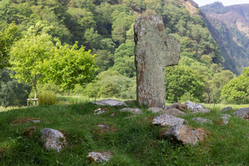 Legendary ancient celtic cross surrounded by stones against moutain range