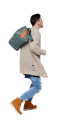 Side view of a running man with a green bag.