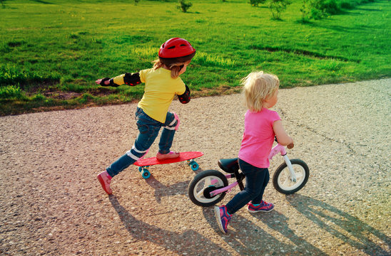 cute happy girls on bike and skateboard ride