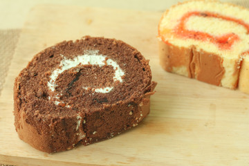 Chocolate and strawberry sweet roll cakes on wood.