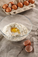 preparation of dough for flat bread. broken egg and flour in a glass bowl