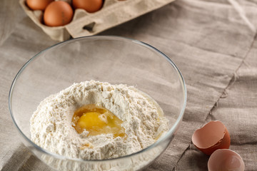 preparation of dough for flat bread. broken egg and flour in a glass bowl