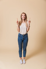 Full length portrait of a happy girl pointing finger up