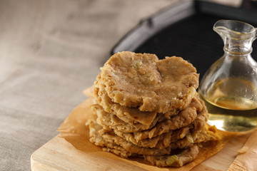 raw flat bread and a carafe of oil on the cutting Board on the background of the grill