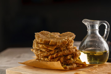 raw flat bread and a carafe of oil on the cutting Board on the background of the grill