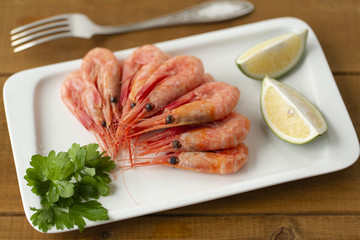 Cooked shrimps on plate with lemon, salt, pepper. Seafood appetizer.