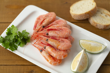 Cooked shrimps on plate with lemon, salt, pepper. Seafood appetizer.