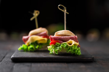 mini sandwiches with lettuce, tomato, yellow cheese and ham, party snacks - obrazy, fototapety, plakaty