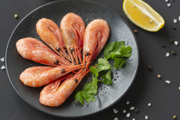 Cooked shrimps on plate with lemon, salt, pepper. Seafood appetizer.