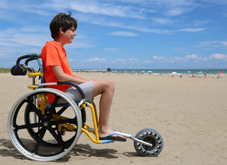 boy looks at the sea from a wheelchair