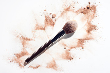 Plush make up brush on white background with scattered face powder