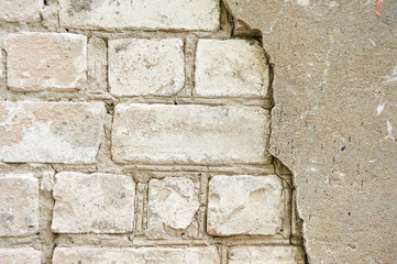 The old wall of white brick with a broken, cracked plaster. Abstract background.