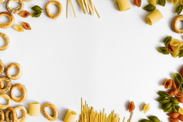 Background with different types of raw pasta and pretzels. Flatlay style, top view, frame, copy...