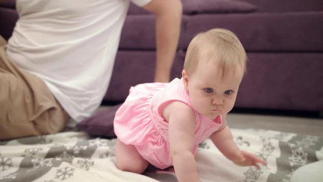 Adorable baby playing with father. Cute toddler girl in pink dress playing with parents at home. Daddy holding little daughter on floor. Infant crawling to mom. Dad and daughter playing together