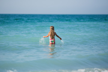 Little girl in the sea. A little girl enters the sea water, rear view.