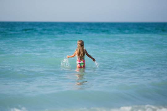 Little girl in the sea. A little girl enters the sea water, rear view.