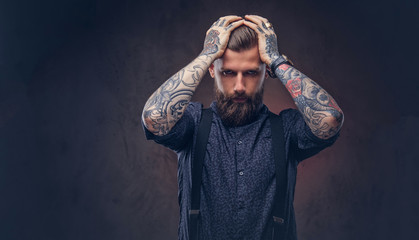 Desperate old-fashioned hipster guy in a blue shirt and suspenders standing in a studio.