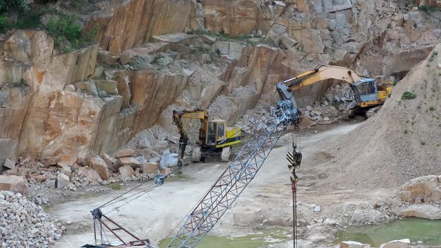 Mining in the granite quarry. Working mining machines - old crane and digger. Mining industry.