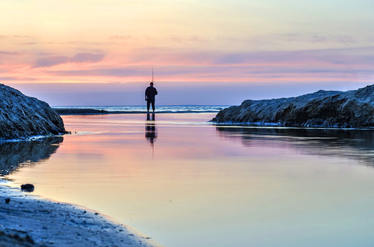 Fisherman fishing on the waterfront and admiring the sunset.