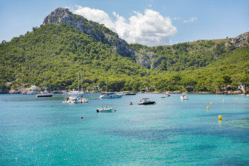 Fototapeta na wymiar Beautiful bay with crystal turquoise water, green mountains, boats on the sea, people on the beach. Picturesque landscape of Formentor, Mallorca, Spain