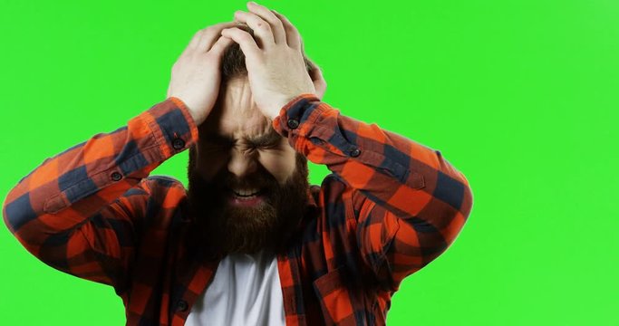 Portrait of the dissapointed caucasian man golding his head with hands like he lost everything. Green screen. Chroma key.
